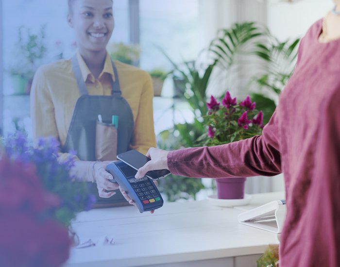 Imagem de uma florista onde se vê um cliente a fazer o pagamento no terminal de pagamento de forma fácil através da wallet.